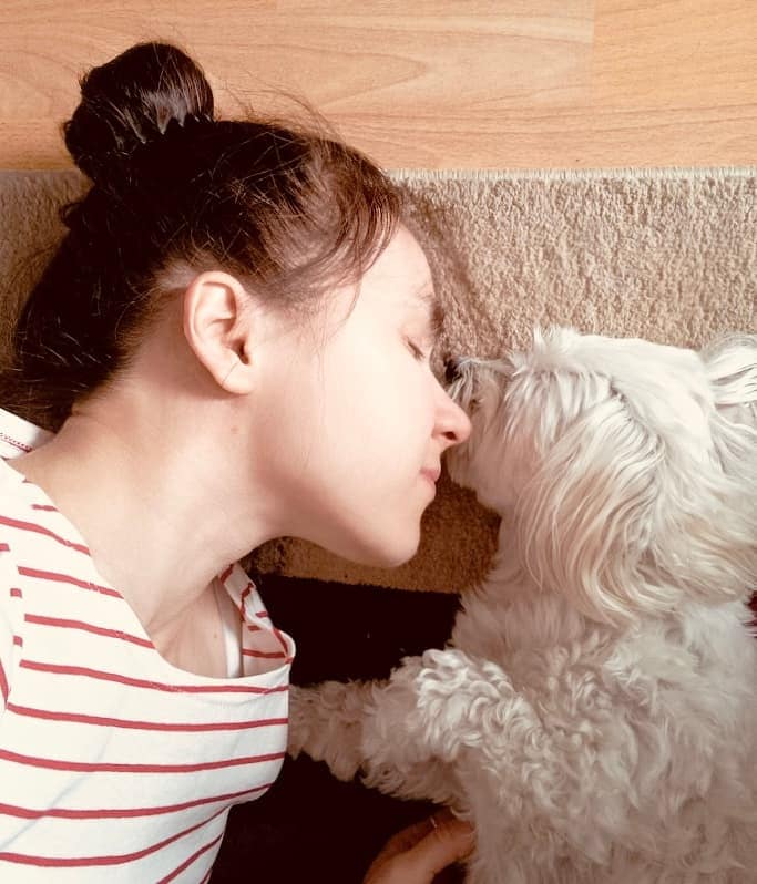 Artist Liene lying on carpet together with her Maltese dog